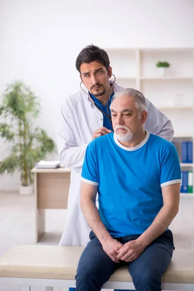 Vecchio paziente maschio in visita giovane medico maschio — Foto Stock