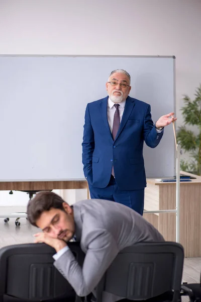 Vieil homme d'affaires et jeune employé masculin devant le tableau blanc — Photo