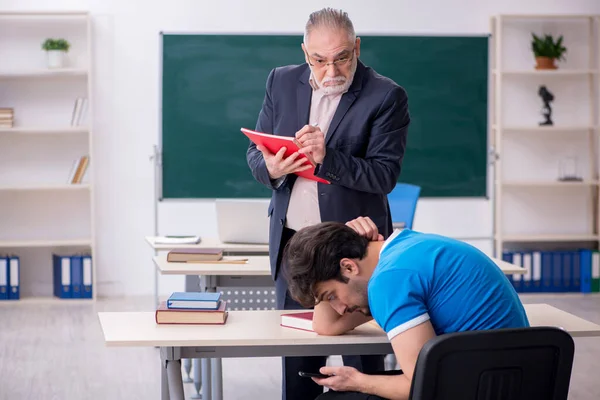 Stary nauczyciel i młody student uzależniony od telefonów w klasie — Zdjęcie stockowe