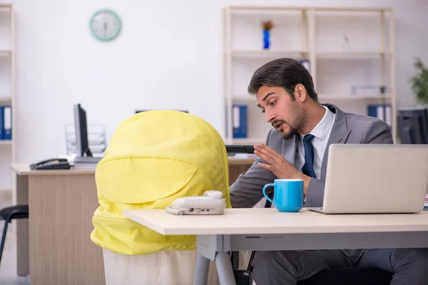 Joven empleado masculino que cuida a recién nacido en el lugar de trabajo — Foto de Stock