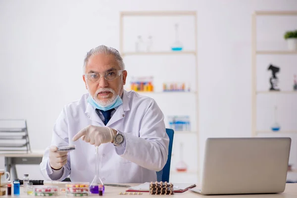 Old male chemist in drug synthesis concept — Stock Photo, Image