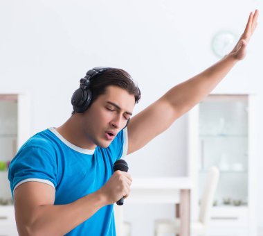Genç yakışıklı adam evde karaoke yapıyor.