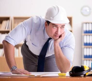 Ofiste çizimler üzerinde çalışan bir mühendis.