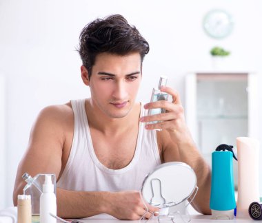 Genç yakışıklı adam aynaya bakıyor.