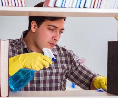 Kitaplıktaki tozları temizleyen adam