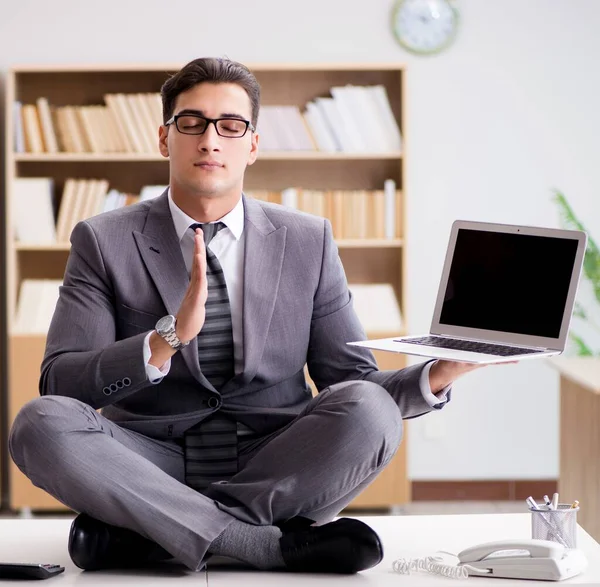 Молодой бизнесмен медитирует в офисе — стоковое фото