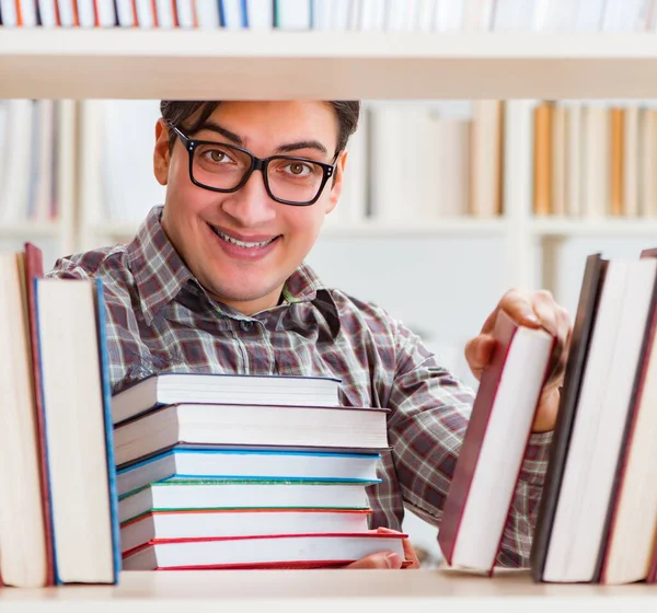 Jonge student op zoek naar boeken in universiteitsbibliotheek — Stockfoto