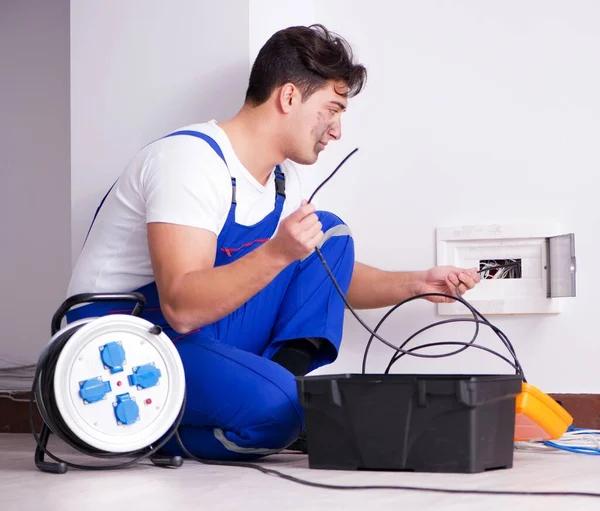 Divertido joven electricista trabajando en zócalo en casa — Foto de Stock