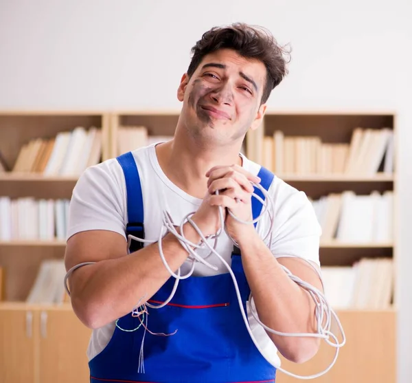 Kablolara dolanmış komik genç elektrikçi. — Stok fotoğraf