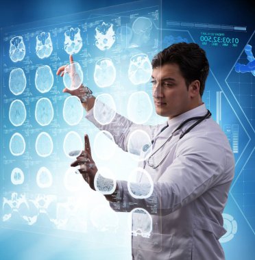 Erkek doktor MRI taramasının röntgenini çekiyor.