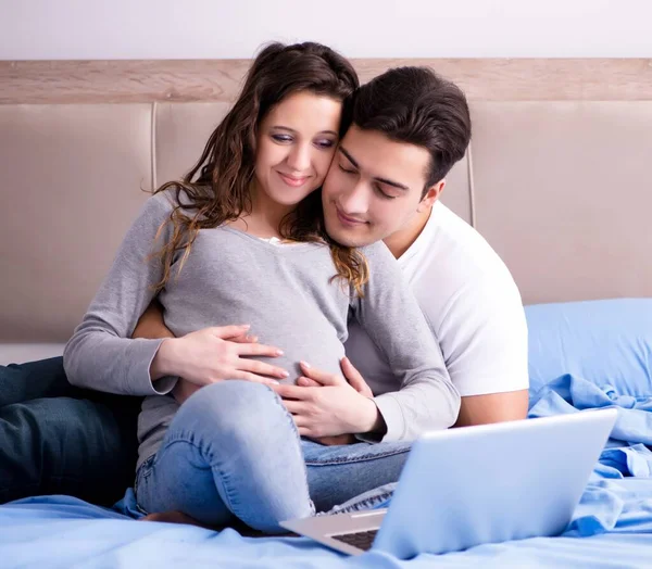 Ung familj med gravid fru väntar barn i sängen — Stockfoto