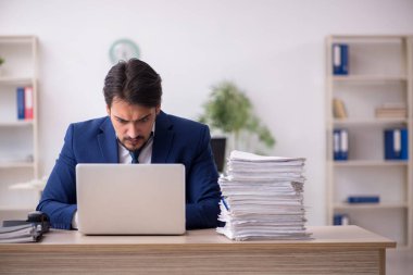 Ofisteki aşırı işten memnun olmayan genç bir erkek işçi.