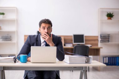 Genç erkek çalışan işyerinde oturuyor.