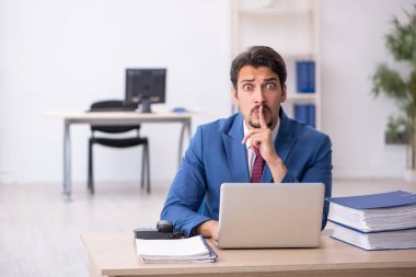 Ofisteki aşırı işten memnun olmayan genç bir erkek işçi.