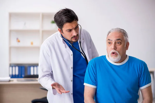 Vecchio paziente maschio in visita giovane medico maschio — Foto Stock