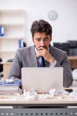 Genç bir erkek çalışan ve ofiste çok fazla iş var.