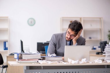 Genç bir erkek çalışan ve ofiste çok fazla iş var.