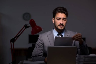 Genç erkek çalışan ofiste geç saatlere kadar çalışıyor.