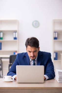 Genç bir erkek çalışan ve ofiste çok fazla iş var.