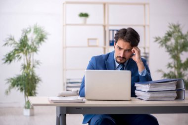 Genç bir erkek çalışan ve ofiste çok fazla iş var.