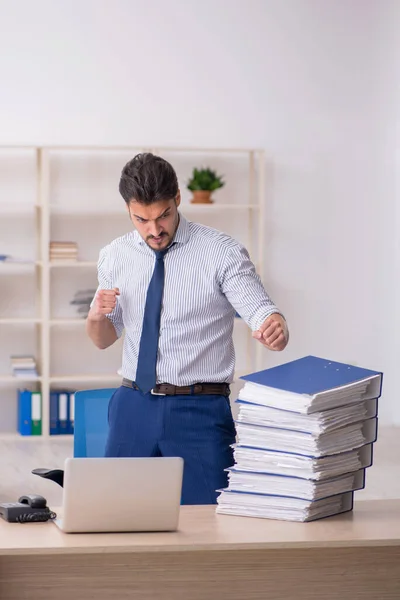 Joven empleado masculino y demasiado trabajo en la oficina — Foto de Stock