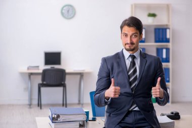 Genç erkek çalışan işyerinde oturuyor.