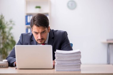 Genç erkek çalışan işyerinde oturuyor.