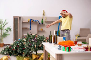 Genç adam Noel partisinden sonra daireyi temizliyor.