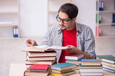 Genç bir erkek öğrenci ve sınıfta çok fazla kitap var.