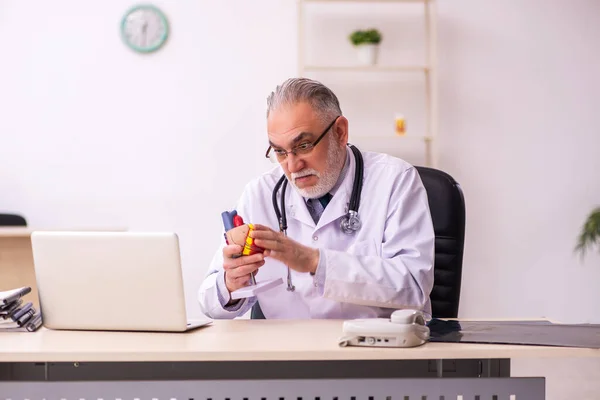 Aged male doctor cardiologist working in the clinic — Stock Photo, Image