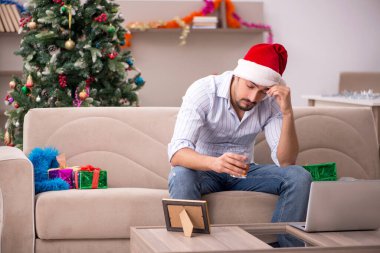 Genç adam Noel 'i evde yalnız kutluyor.