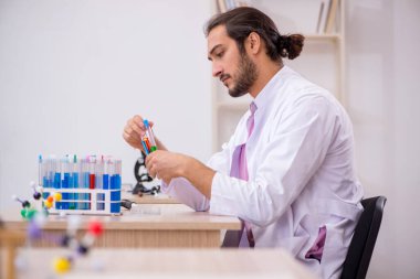 Sınıftaki masada oturan genç bir kimyager.