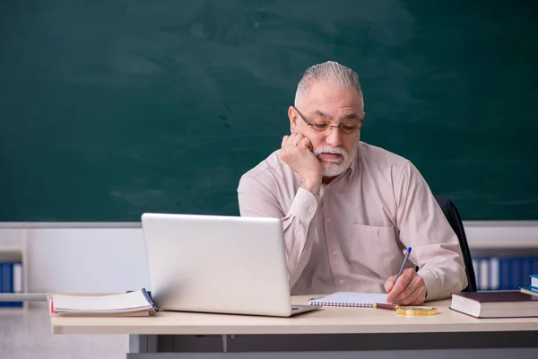 Gammal manlig lärare framför svarta tavlan — Stockfoto