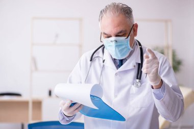 Klinikte çalışan yaşlı erkek doktor.