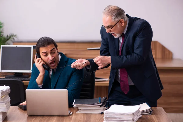 Velho empregador masculino e jovem assistente no conceito de bullying — Fotografia de Stock