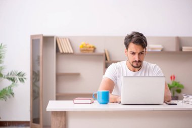 Genç erkek çalışan salgın sırasında evden çalışıyor.