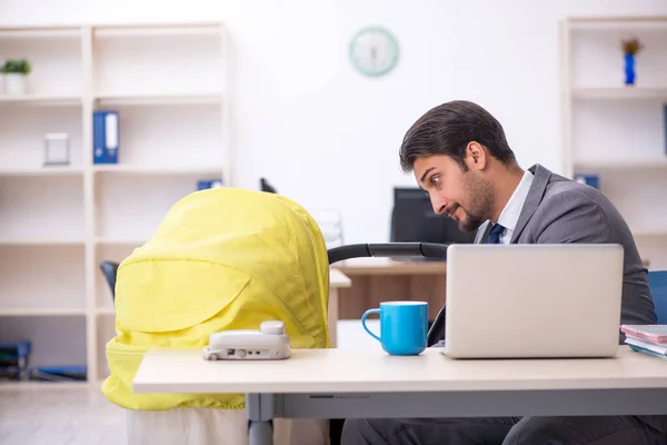 Young male employee looking after new born at workplace — Stock Photo, Image