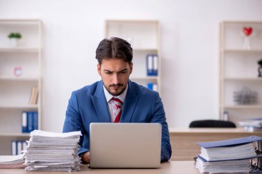 Genç bir erkek çalışan ve ofiste çok fazla iş var.