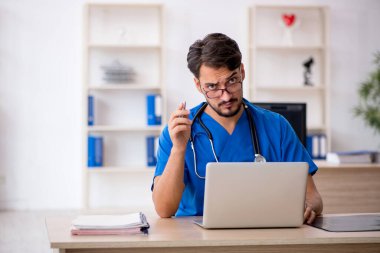 Klinikte çalışan genç erkek doktor.