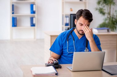 Klinikte çalışan genç erkek doktor.