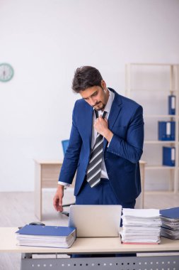 Genç bir erkek çalışan ve ofiste çok fazla iş var.