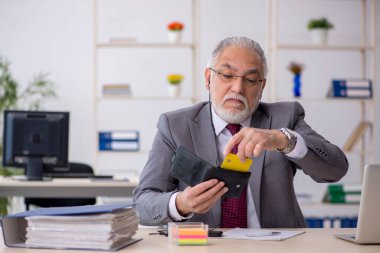 Ofiste kredi kartı tutan yaşlı bir erkek.