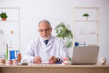 Klinikte çalışan yaşlı erkek dişçi.