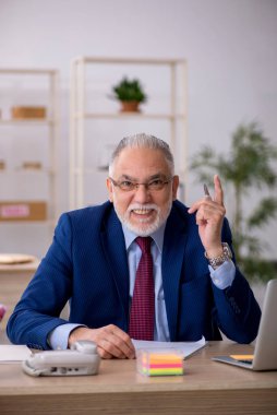 Ofiste çalışan yaşlı bir erkek.