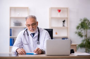 Klinikte çalışan yaşlı erkek doktor.