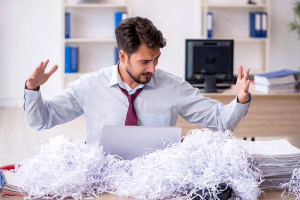 Young male employee and a lot of cut papers in the office — Stock Photo, Image