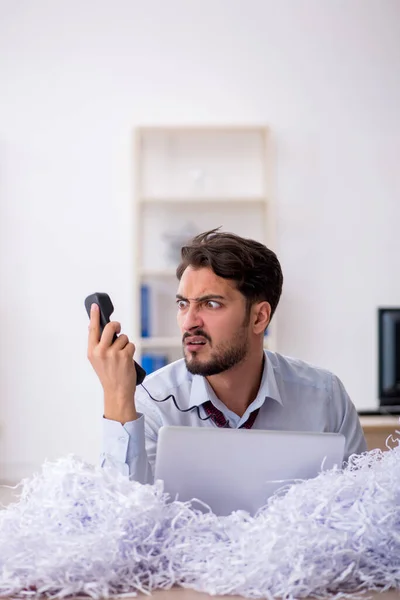 Jeune employé masculin et beaucoup de papiers coupés dans le bureau — Photo