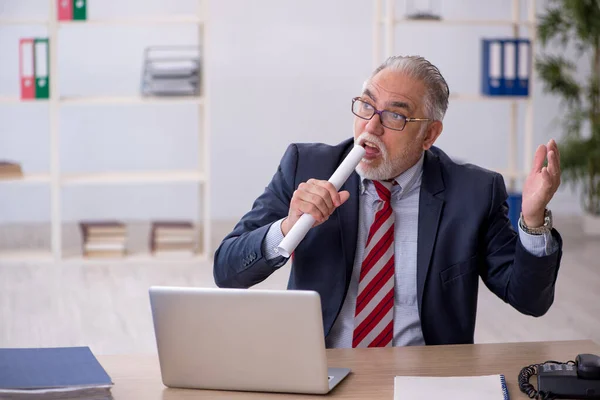 Oude mannelijke werknemer die op kantoor werkt — Stockfoto