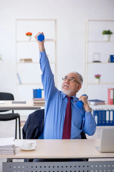 Viejo empleado masculino haciendo ejercicios deportivos durante el descanso —  Fotos de Stock