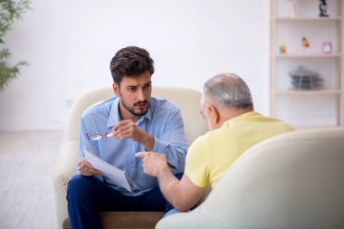 Yaşlı adam genç erkek psikoterapisti ziyaret ediyor.